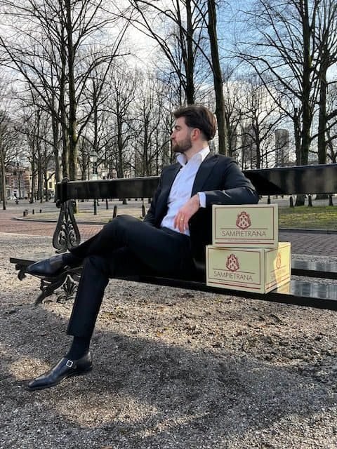 Man met Lamprna wijn relatiegeschenken op parkbank Den Haag Vini di Villani stijl